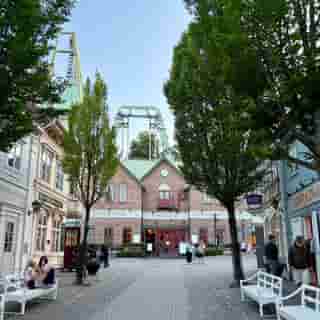 Die Station der Lisebergbanan mit rotem Backsteingebäude und grünen Achterbahnschienen im Freizeitpark Liseberg.