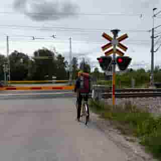 Reisender mit gelbem Leihvelo wartet an einem Bahnübergang in Gällivare.