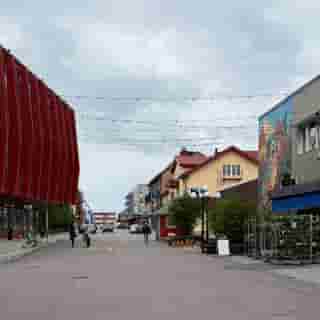 Strasse im Zentrum von Gällivare mit alten und neuen Gebäuden und einer Wandmalerei.