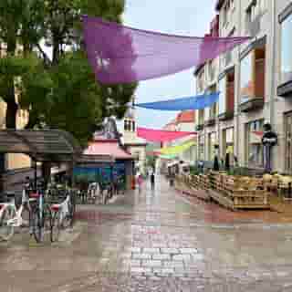 Nasses Kopfsteinpflaster, gedeckte Farben und Menschen mit Schirmen im Stadtzentrum von Östersund.