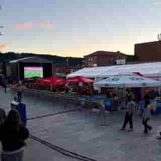 Ausgelassene Menschen schauen ein Fussballspiel auf Grossleinwand am Hauptplatz von Östersund.