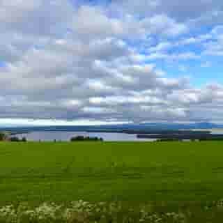 Blaue Lücken zwischen Wolken über Östersund; die Sonne bricht durch und taucht die Häuser in warmes Licht.