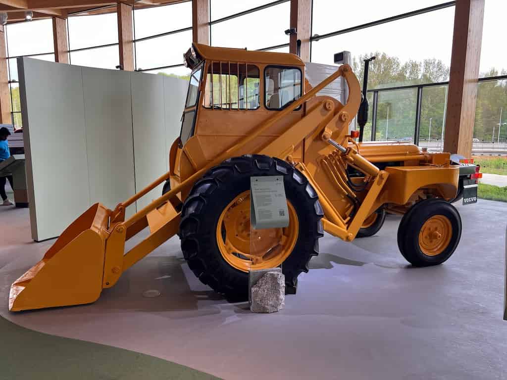 Ein gelber Frontlader präsentiert in einer modernen Ausstellungshalle. Das Fahrzeug ist auf einem sauberen, polierten Betonboden geparkt.